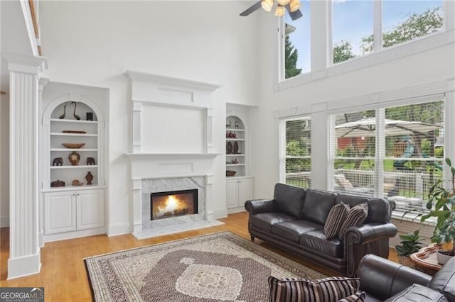 1029 Ector Dr NW, Kennesaw, GA 30152 - living area featuring a towering ceiling, built in features, light wood-type flooring, a premium fireplace, and a ceiling fan