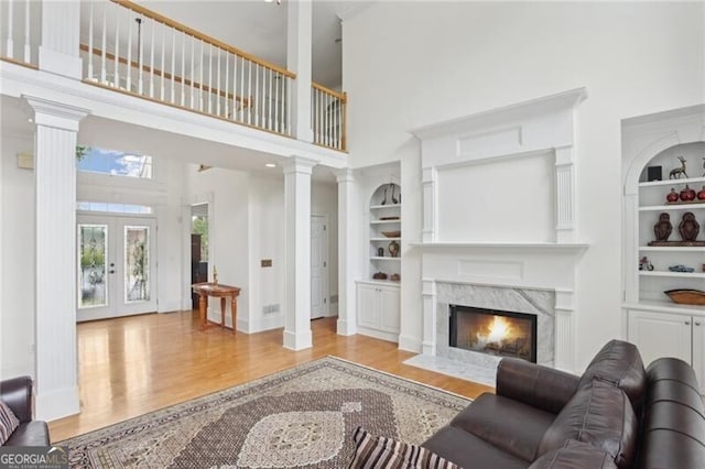 1029 Ector Dr NW, Kennesaw, GA 30152 - living area with built in shelves, a towering ceiling, light wood-type flooring, baseboards, and a fireplace