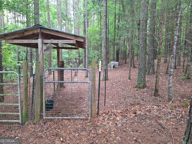 gate featuring a forest view and fence