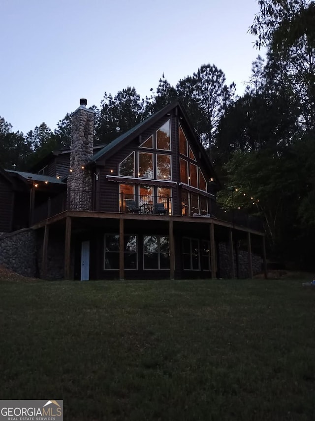 rear view of property featuring a lawn, a deck, and a chimney