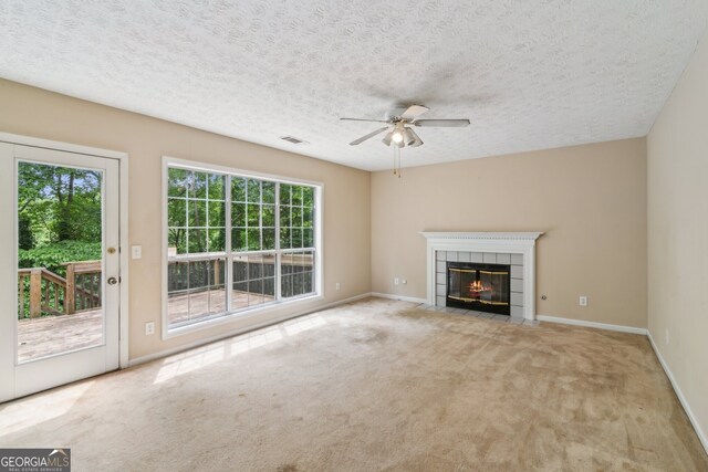111 Trellis Ct, Acworth, GA 30101 - unfurnished living room with healthy amount of natural light, a tiled fireplace, a ceiling fan, carpet floors, and a textured ceiling
