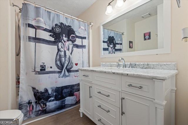 1154 Pinebrook Rd, Auburn, GA 30011 - bathroom with wood finished floors, vanity, a textured ceiling, toilet, and curtained shower