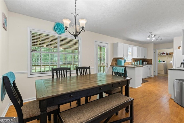 1154 Pinebrook Rd, Auburn, GA 30011 - dining room featuring a chandelier, independent washer and dryer, light wood-style flooring, a textured ceiling, and baseboards