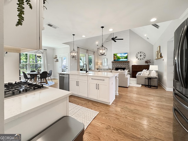 35 Perkins Cv, Senoia, GA 30276 - kitchen with a brick fireplace, appliances with stainless steel finishes, a ceiling fan, white cabinets, and light wood-style floors
