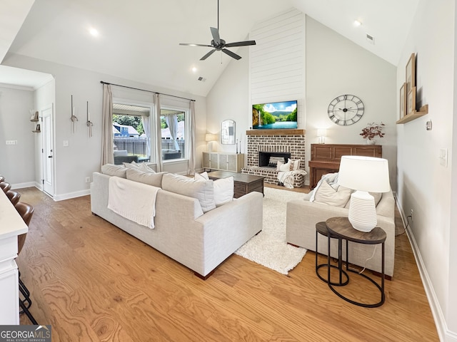 35 Perkins Cv, Senoia, GA 30276 - living room with a fireplace, light wood-style flooring, high vaulted ceiling, a ceiling fan, and baseboards