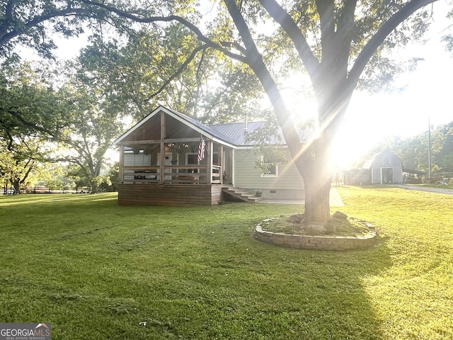 rear view of property featuring crawl space, a sunroom, a lawn, and metal roof