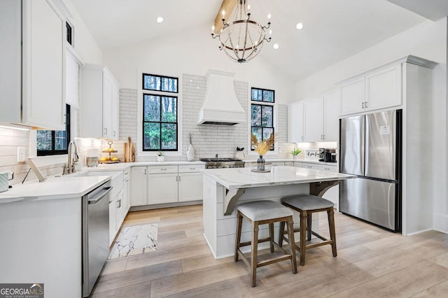 201 Dobbs Rd, Woodstock, GA 30188 - kitchen featuring appliances with stainless steel finishes, custom exhaust hood, a center island, light wood finished floors, and a breakfast bar area
