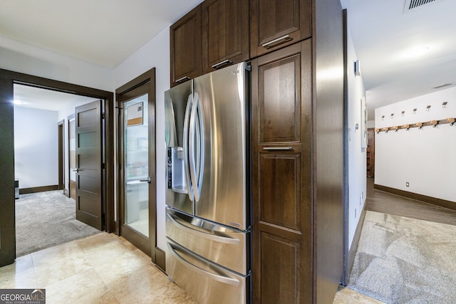 kitchen featuring stainless steel fridge with ice dispenser, dark brown cabinets, light carpet, and baseboards