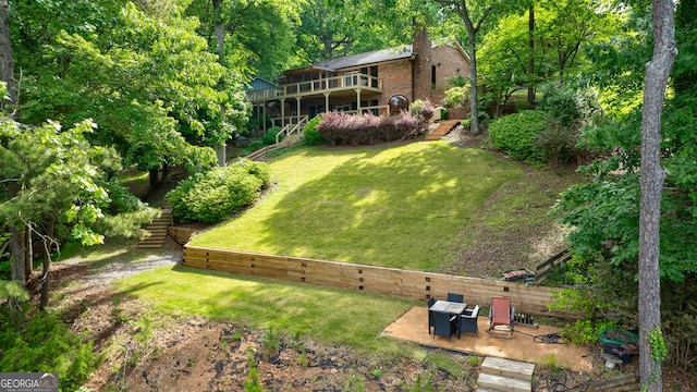 view of grassy yard featuring stairs, a patio, and a wooden deck