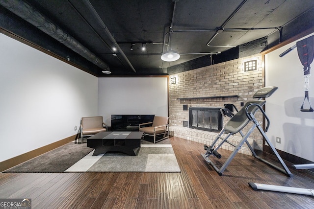 living room with baseboards, hardwood / wood-style floors, a fireplace, and brick wall