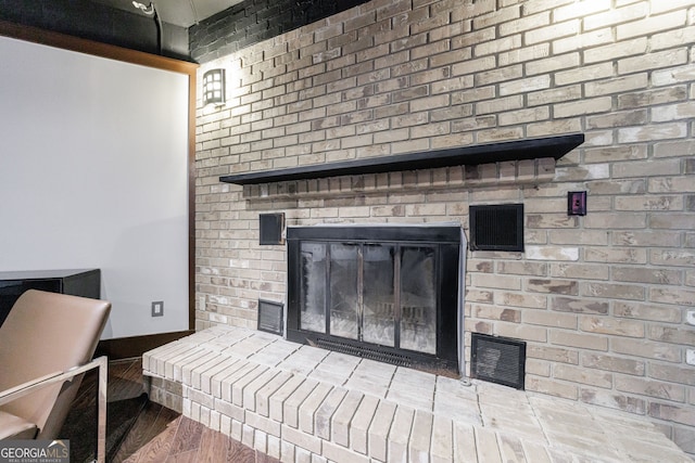 detailed view of wood finished floors and a brick fireplace