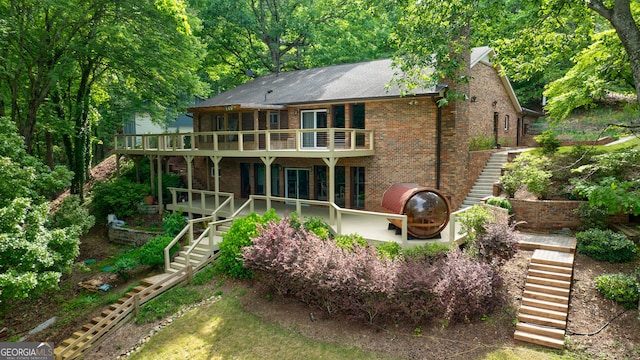 rear view of property featuring stairway, brick siding, and roof with shingles