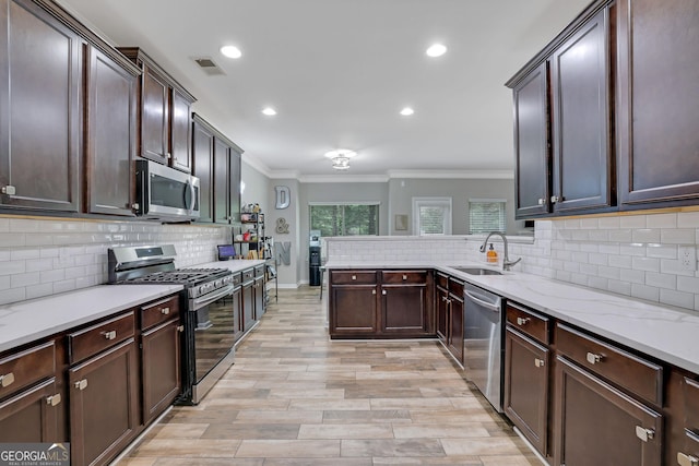 4251 Haywater Cv, Buford, GA 30519 - kitchen with appliances with stainless steel finishes, a sink, crown molding, tasteful backsplash, and light wood-style floors