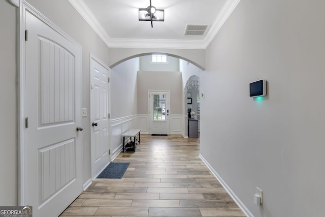 4251 Haywater Cv, Buford, GA 30519 - entrance foyer with arched walkways, ornamental molding, light wood-type flooring, and wainscoting