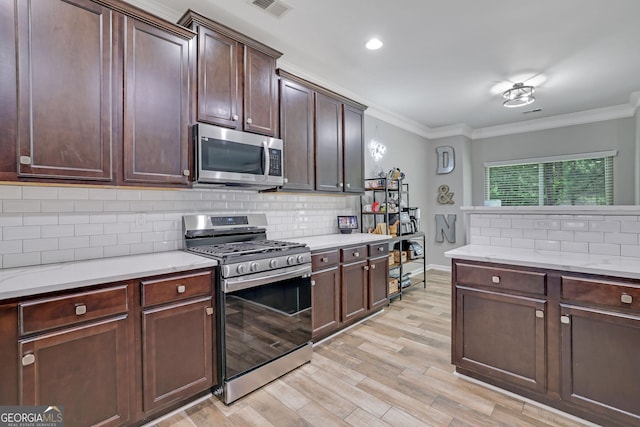 4251 Haywater Cv, Buford, GA 30519 - kitchen with stainless steel appliances, crown molding, light wood finished floors, tasteful backsplash, and dark brown cabinets
