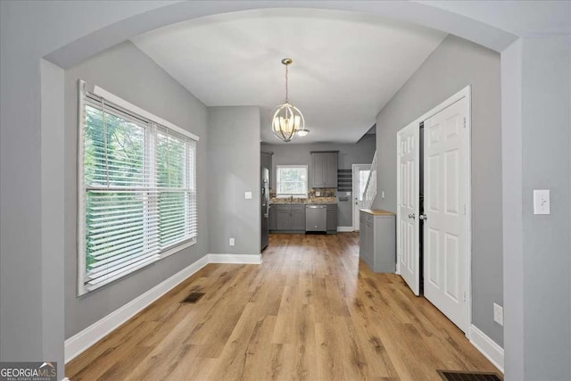 3111 Jones St, East Point, GA 30344 - unfurnished dining area with arched walkways, a chandelier, light wood finished floors, and baseboards