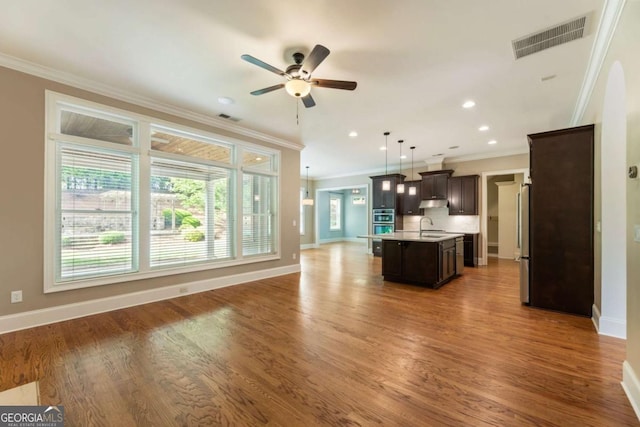 2165 Mcfarlin Ln, Alpharetta, GA 30004 - kitchen featuring a sink, light countertops, open floor plan, crown molding, and dark brown cabinetry