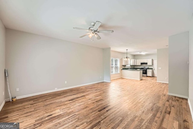 558 Elbridge Dr NW, Atlanta, GA 30318 - unfurnished living room featuring light wood-style flooring, ceiling fan, and a chandelier