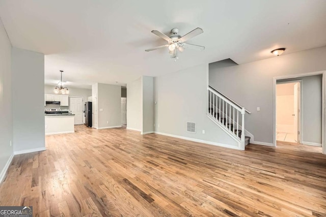 558 Elbridge Dr NW, Atlanta, GA 30318 - unfurnished living room with stairway, light wood-type flooring, a ceiling fan, and a chandelier