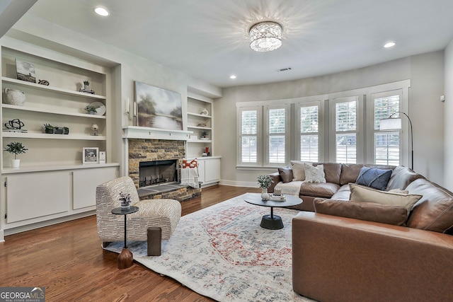 living area with dark wood-type flooring, a stone fireplace, recessed lighting, baseboards, and built in features
