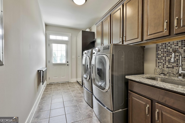 clothes washing area featuring washer and clothes dryer, cabinet space, baseboards, and light tile patterned flooring