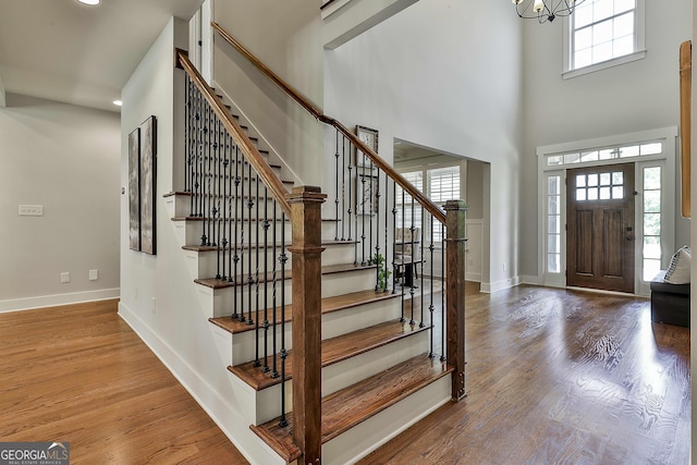 foyer with stairway, baseboards, wood finished floors, a towering ceiling, and recessed lighting