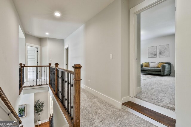 hallway featuring carpet, an upstairs landing, recessed lighting, and baseboards