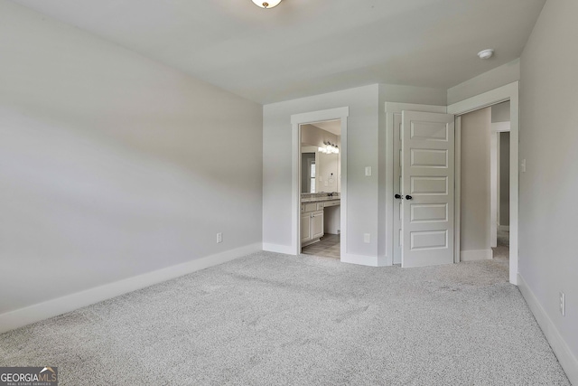 unfurnished bedroom featuring light colored carpet, baseboards, and connected bathroom