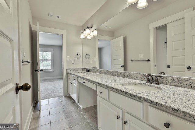 full bath featuring baseboards, double vanity, and tile patterned floors