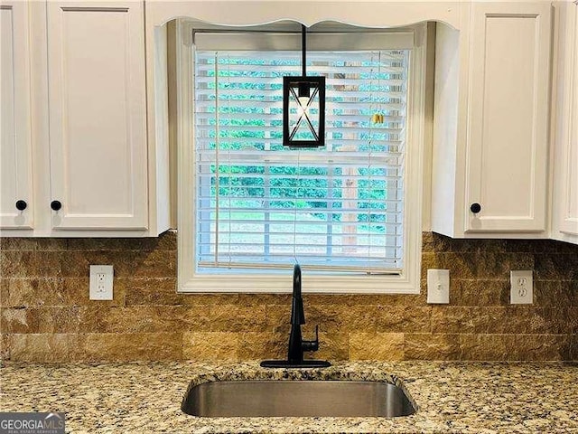 107 Oconnor Dr, Dallas, GA 30157 - kitchen view of a sink, white cabinets, backsplash, and light stone countertops