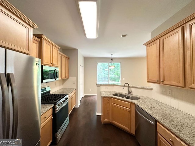 kitchen featuring appliances with stainless steel finishes, a sink, a peninsula, backsplash, and dark wood-type flooring