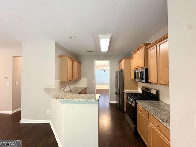 kitchen with appliances with stainless steel finishes, a peninsula, baseboards, light stone countertops, and recessed lighting