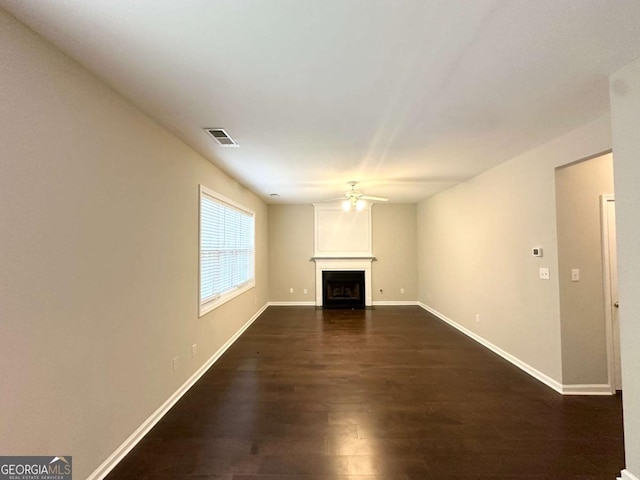unfurnished living room featuring ceiling fan, dark wood-style flooring, a fireplace, and baseboards