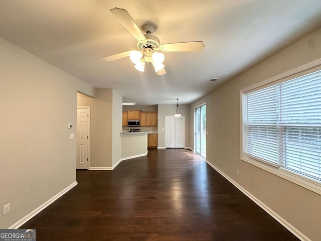 unfurnished living room featuring ceiling fan, dark wood-style flooring, and baseboards