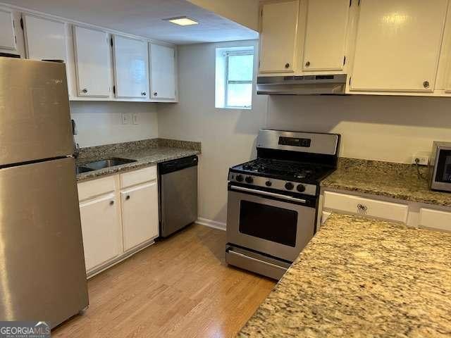 1233 Woodland Ave NE Unit 5, Atlanta, GA 30324 - kitchen with stainless steel appliances, under cabinet range hood, light wood-style floors, and white cabinetry
