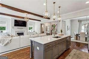 3617 Carson Ln SE, Smyrna, GA 30080 - kitchen featuring dark wood-type flooring, open floor plan, light countertops, a kitchen island with sink, and a fireplace