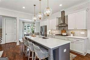 3617 Carson Ln SE, Smyrna, GA 30080 - kitchen featuring wall chimney exhaust hood, a sink, dark wood-style flooring, an island with sink, and a breakfast bar