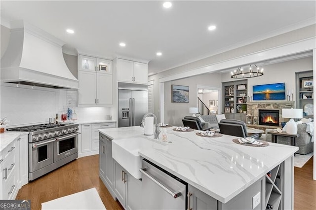 5844 Yoshino Cherry Ln, Braselton, GA 30517 - kitchen featuring premium appliances, premium range hood, a sink, open floor plan, and a center island with sink