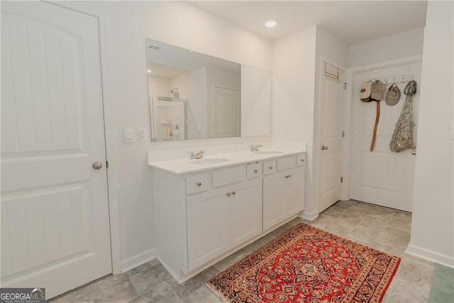 bathroom with double vanity, baseboards, and a shower