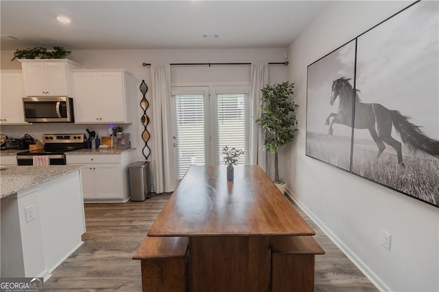 kitchen with appliances with stainless steel finishes, white cabinets, wood finished floors, decorative backsplash, and recessed lighting