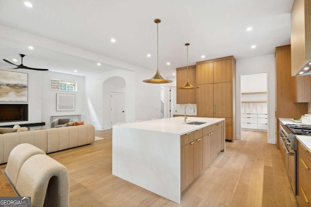 1287 Star Dr NE, Brookhaven, GA 30319 - kitchen featuring a sink, high end stainless steel range, a ceiling fan, arched walkways, and light wood finished floors