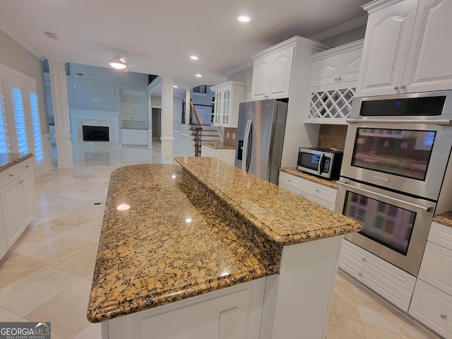 45 Mountain Crest Dr, Oxford, GA 30054 - kitchen with stainless steel appliances, ornate columns, light stone countertops, a kitchen island, and ornamental molding