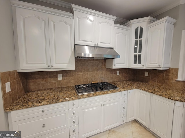 45 Mountain Crest Dr, Oxford, GA 30054 - kitchen with under cabinet range hood, white cabinetry, dark stone counters, backsplash, and crown molding