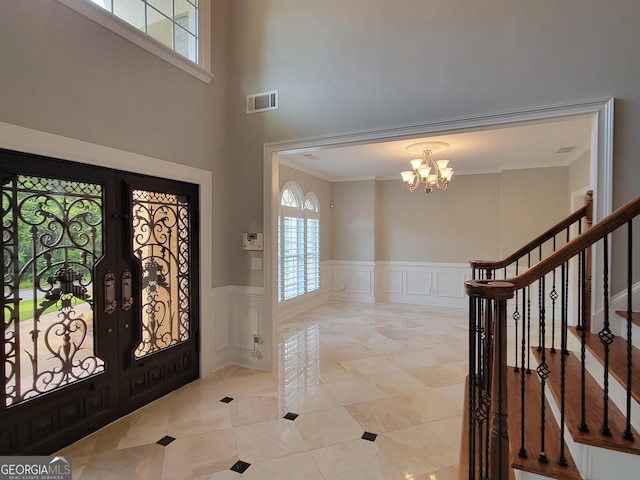45 Mountain Crest Dr, Oxford, GA 30054 - foyer entrance with a chandelier, crown molding, a wainscoted wall, a decorative wall, and tile patterned floors
