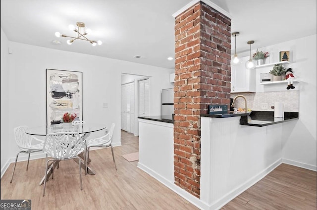 251 Aurora Ave NW, Atlanta, GA 30314 - kitchen featuring dark countertops, freestanding refrigerator, light wood finished floors, a chandelier, and white cabinets