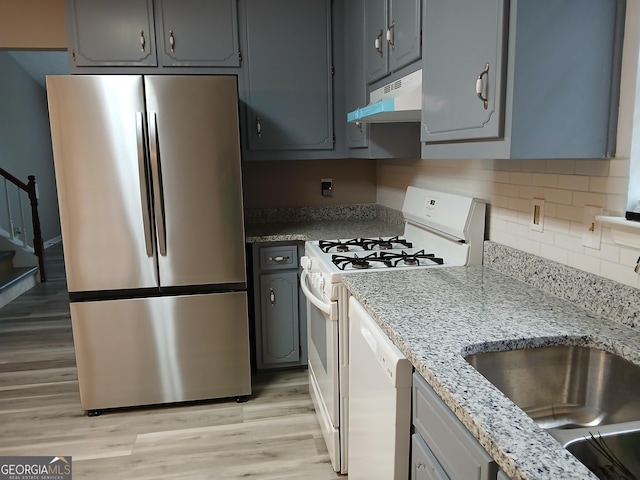 5517 Rock Shoals Way, Atlanta, GA 30349 - kitchen with white appliances, under cabinet range hood, a sink, light wood-style floors, and tasteful backsplash