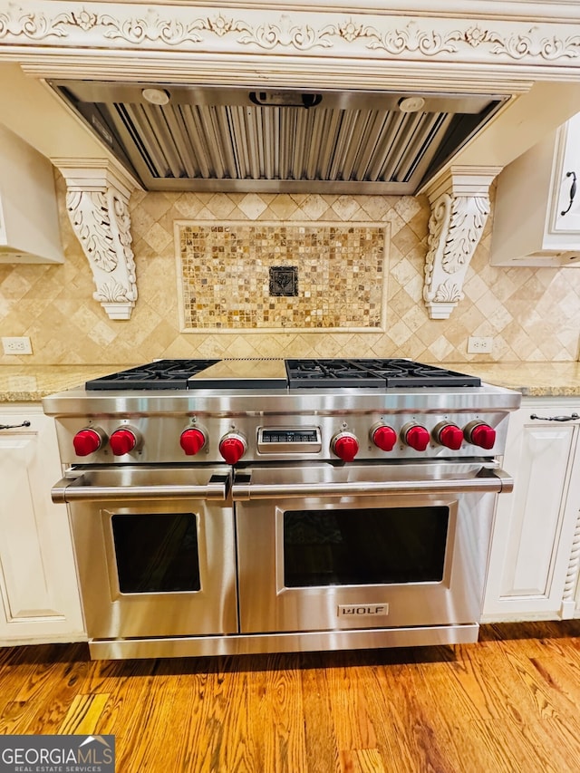 1023 Little Darby Ln, Suwanee, GA 30024 - kitchen with range with two ovens, custom range hood, backsplash, white cabinets, and light wood-style flooring