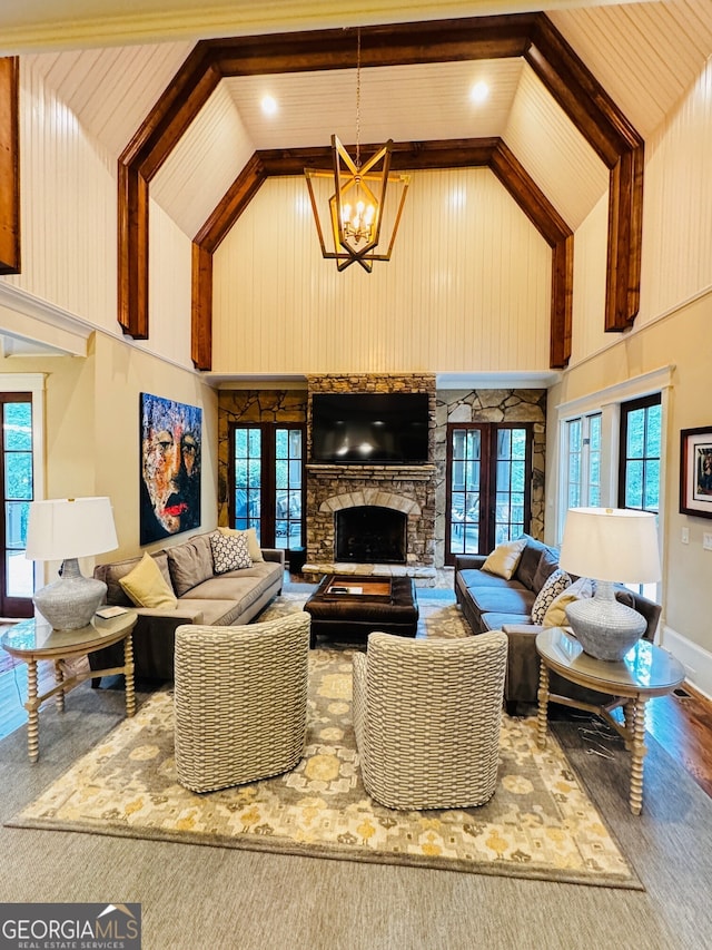1023 Little Darby Ln, Suwanee, GA 30024 - living area featuring high vaulted ceiling, a chandelier, healthy amount of natural light, wood finished floors, and a stone fireplace