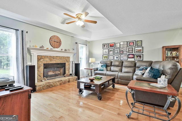55 Hubbard Ct, Newnan, GA 30263 - living room with ceiling fan, plenty of natural light, light wood-style floors, a stone fireplace, and a textured ceiling