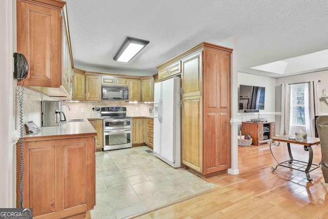 55 Hubbard Ct, Newnan, GA 30263 - kitchen with double oven range, white refrigerator with ice dispenser, black microwave, a sink, and decorative backsplash